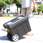 Portable tool chest being wheeled along a sidewalk by a person in casual attire